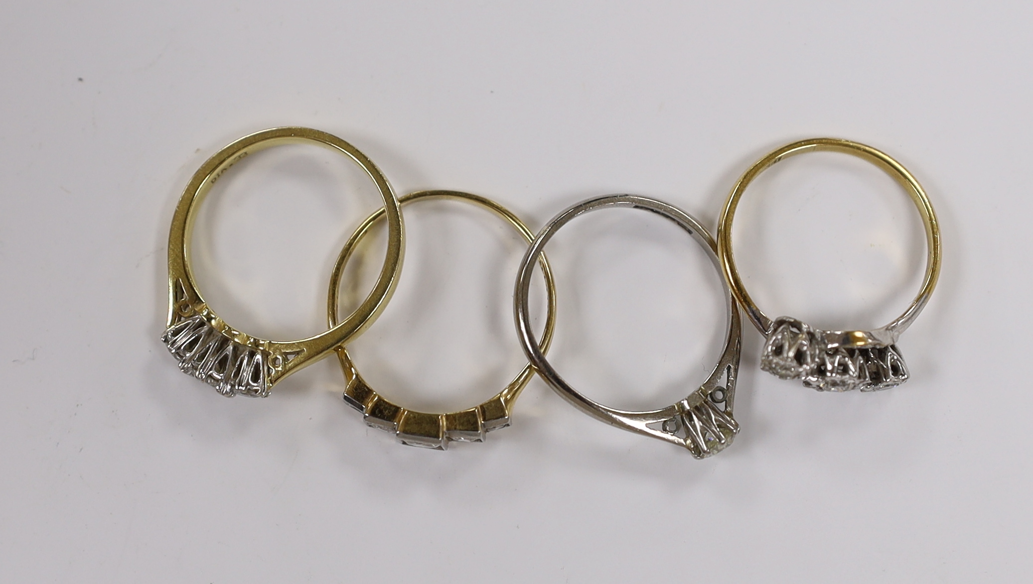 Four assorted 18ct and diamond set rings, including two three stone, a five stone and solitaire, gross weight 10.7 grams.